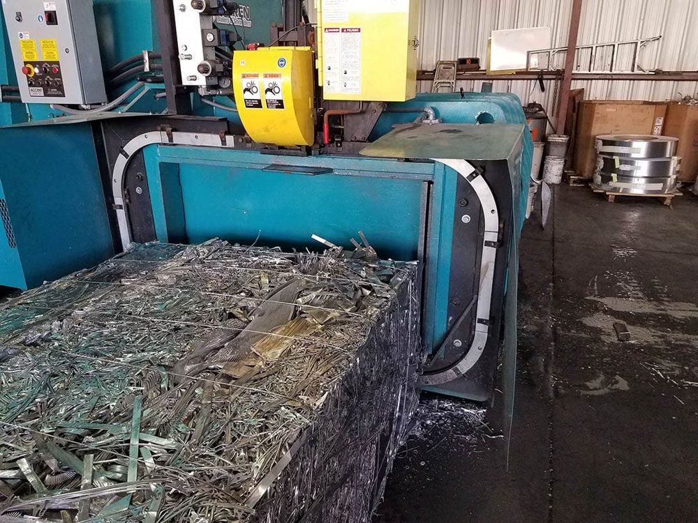 Finished metal bale being ejected from a two-ram baler